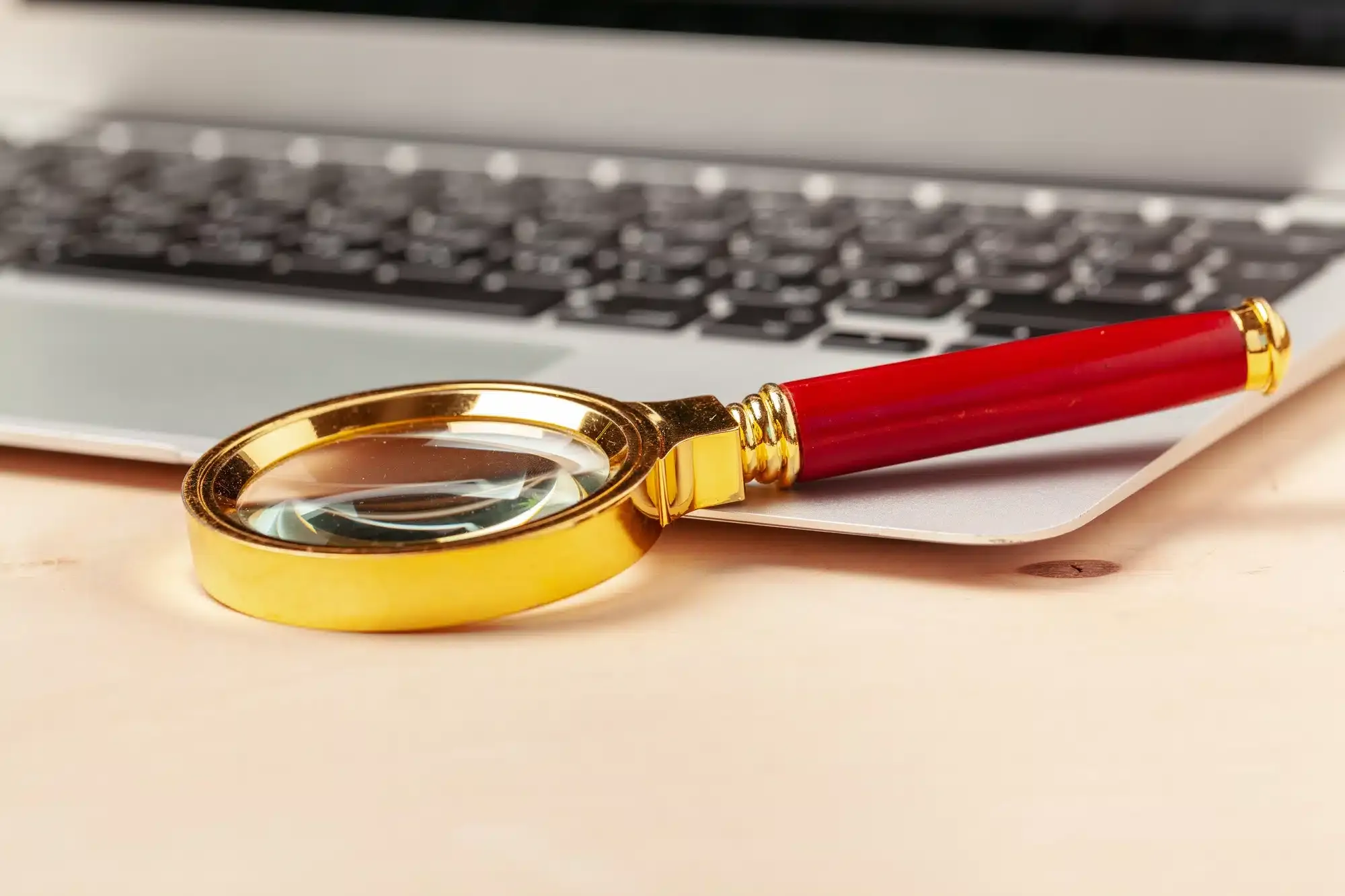 Laptop computer keyboard with magnifying glass, concept of search